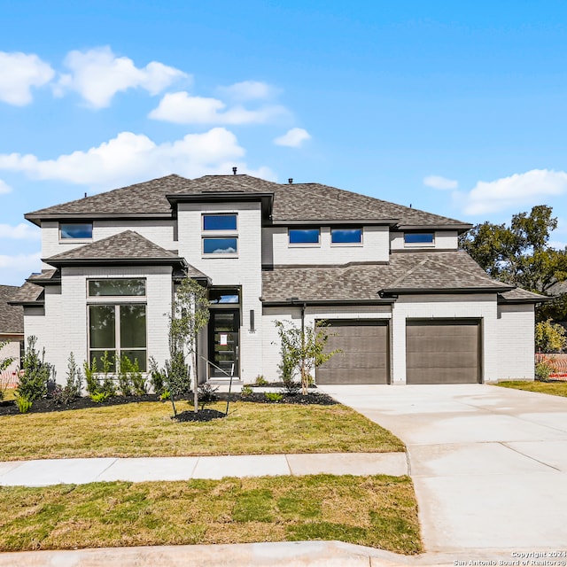 prairie-style house with a garage and a front lawn