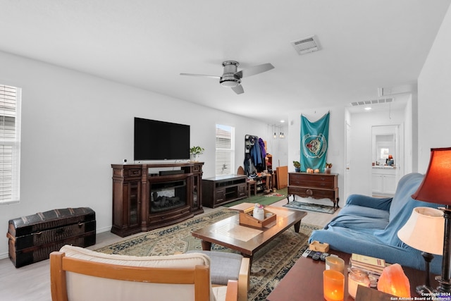 living room featuring ceiling fan, light hardwood / wood-style flooring, and a fireplace