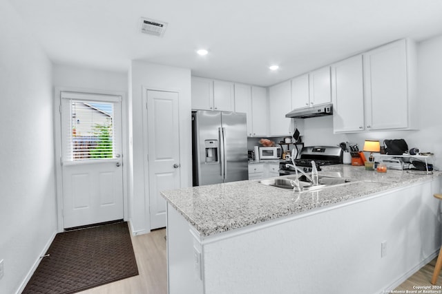 kitchen featuring light stone counters, kitchen peninsula, light hardwood / wood-style flooring, white cabinetry, and stainless steel appliances