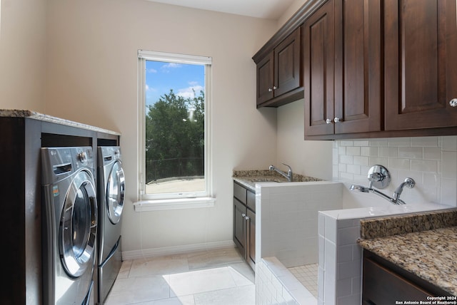 laundry area featuring plenty of natural light, cabinets, light tile patterned floors, and washer and clothes dryer