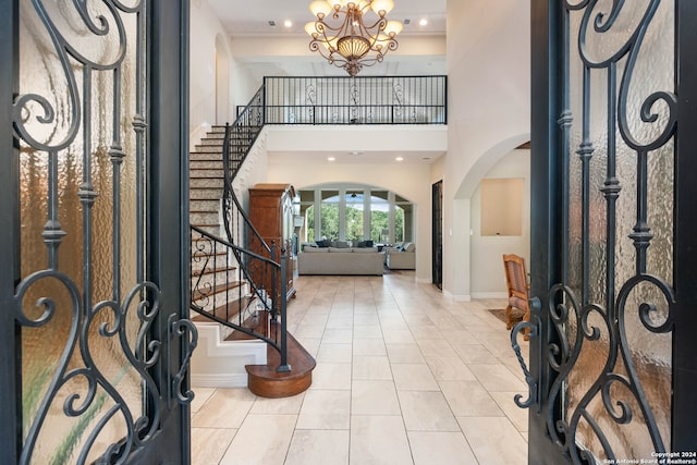 foyer featuring light tile patterned floors, a towering ceiling, and a chandelier