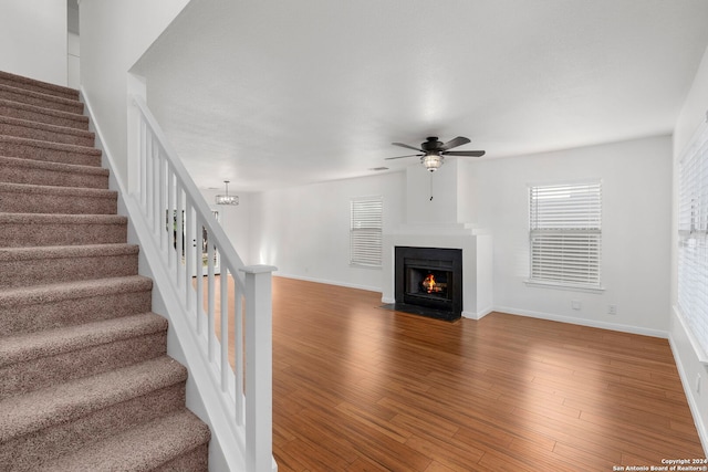 unfurnished living room with wood-type flooring and ceiling fan with notable chandelier