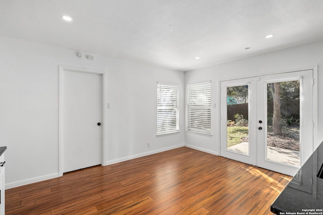 empty room featuring french doors, a textured ceiling, and dark wood-type flooring