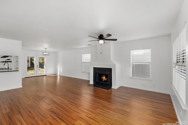 unfurnished living room featuring wood-type flooring and ceiling fan with notable chandelier