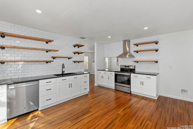 kitchen featuring appliances with stainless steel finishes, wall chimney exhaust hood, dark wood-type flooring, sink, and white cabinetry