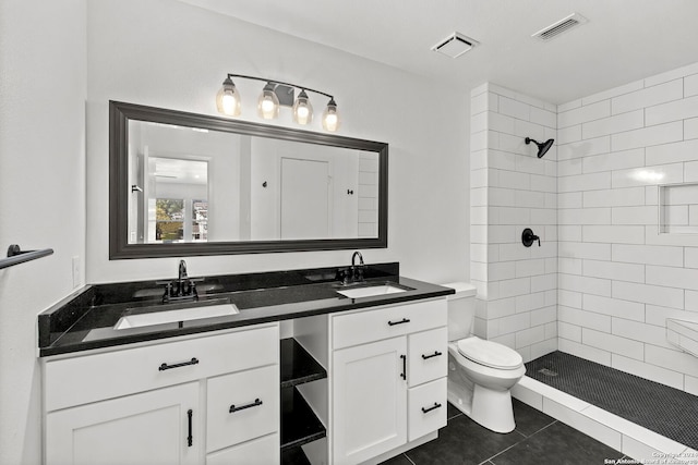 bathroom with tile patterned floors, toilet, a tile shower, and vanity