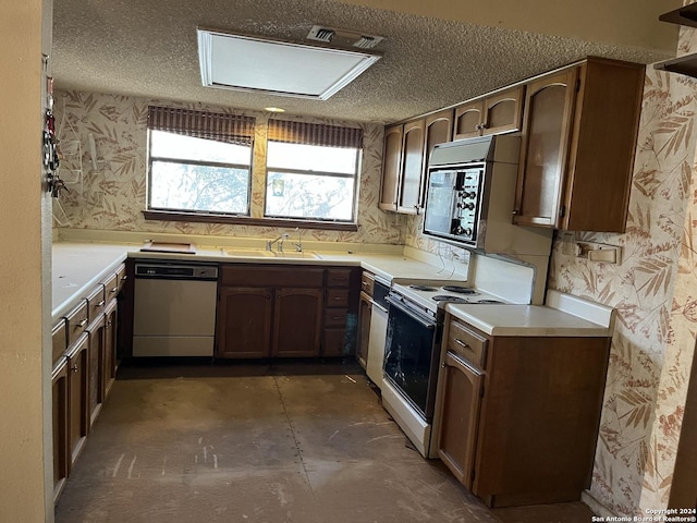 kitchen featuring white electric range oven, a textured ceiling, dishwasher, a sink, and wallpapered walls