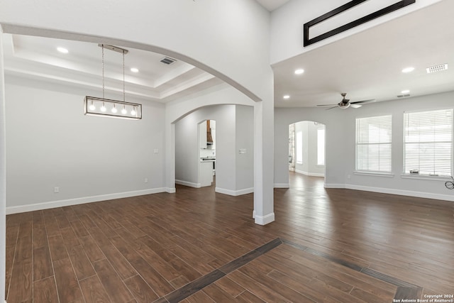 unfurnished living room featuring ceiling fan, dark wood-type flooring, and a raised ceiling