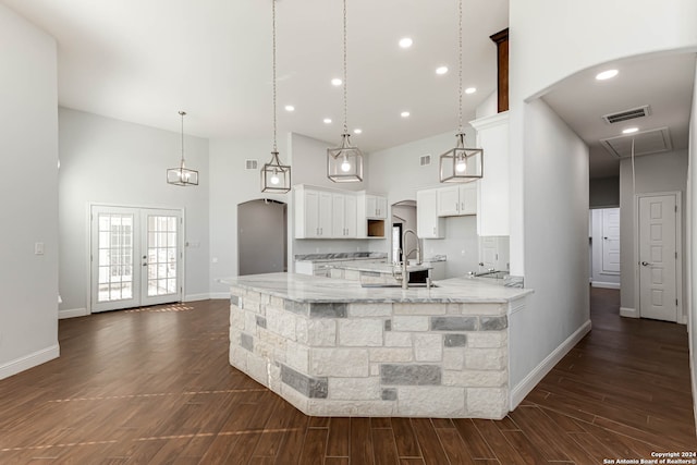 kitchen with light stone counters, dark hardwood / wood-style floors, white cabinets, a high ceiling, and pendant lighting