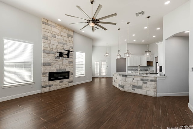 living room featuring ceiling fan, a fireplace, dark wood-type flooring, and a high ceiling