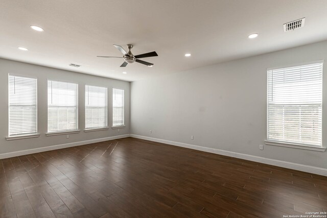 unfurnished room featuring ceiling fan, dark hardwood / wood-style flooring, and a healthy amount of sunlight