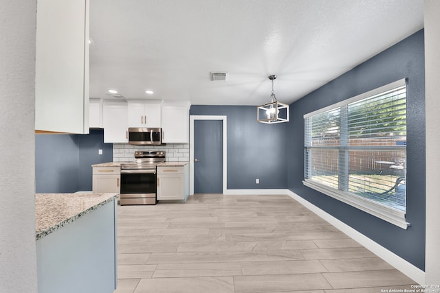 kitchen featuring light hardwood / wood-style floors, pendant lighting, light stone countertops, white cabinets, and appliances with stainless steel finishes