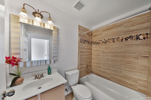 full bathroom featuring a textured ceiling, toilet, vanity, and tiled shower / bath combo