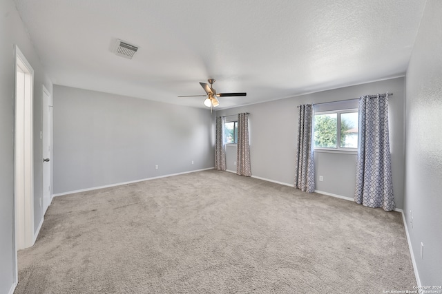 carpeted spare room featuring ceiling fan and a textured ceiling