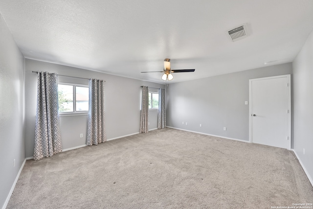 unfurnished room featuring ceiling fan, plenty of natural light, and light colored carpet