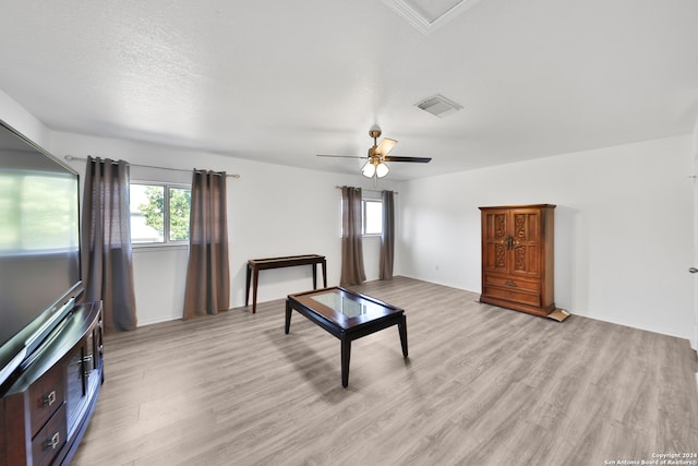 living room featuring plenty of natural light, light hardwood / wood-style floors, a textured ceiling, and ceiling fan