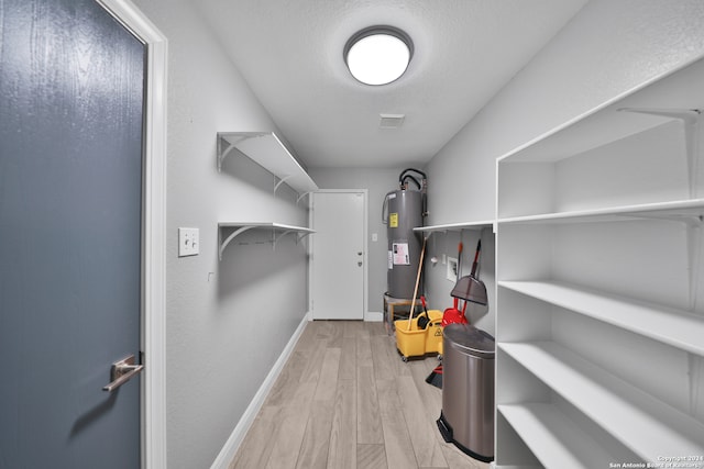 walk in closet featuring electric water heater and light wood-type flooring