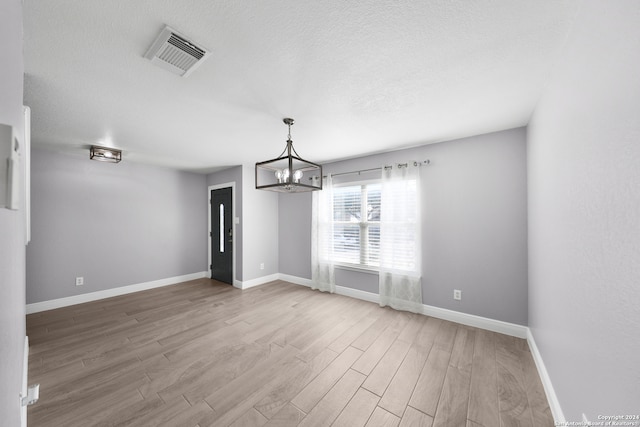 unfurnished dining area featuring hardwood / wood-style flooring, a notable chandelier, and a textured ceiling