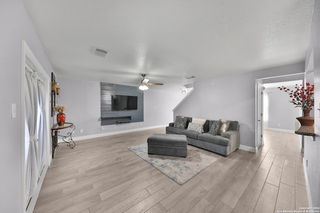 living room with light hardwood / wood-style floors, a textured ceiling, and ceiling fan