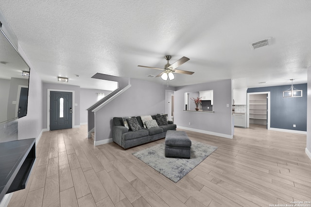 living room featuring ceiling fan, light hardwood / wood-style floors, and a textured ceiling