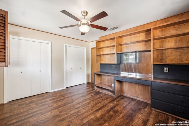 unfurnished office with ceiling fan, dark hardwood / wood-style flooring, and built in desk