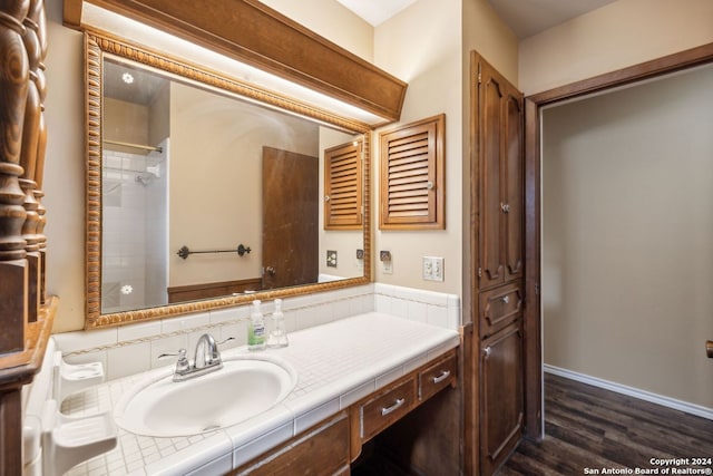 bathroom featuring hardwood / wood-style flooring, vanity, and a shower