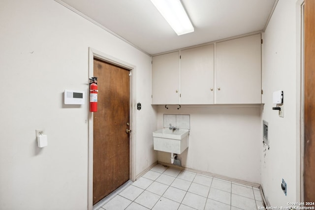 clothes washing area with cabinets, washer hookup, sink, and light tile patterned floors