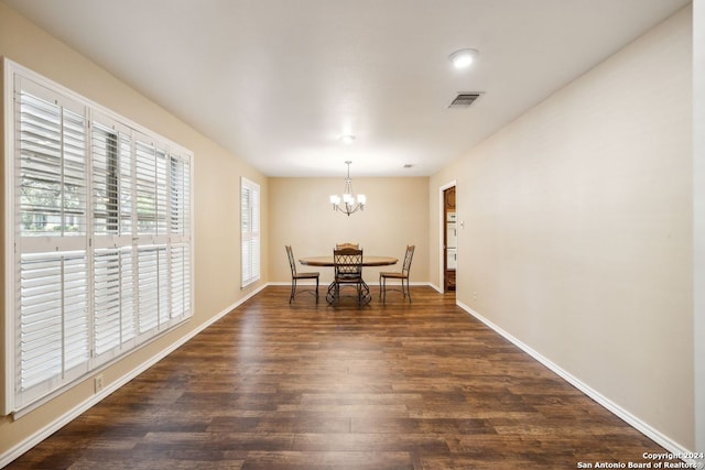 dining area featuring dark wood-type flooring and a notable chandelier