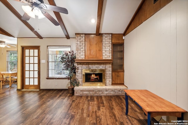 unfurnished living room with ceiling fan, vaulted ceiling with beams, wooden walls, a fireplace, and dark hardwood / wood-style flooring