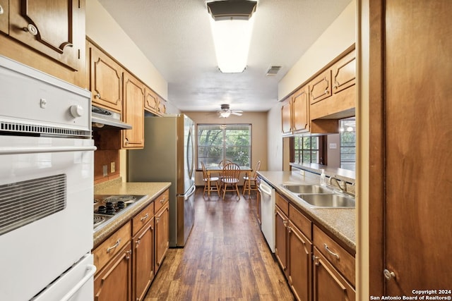 kitchen with sink, dark hardwood / wood-style flooring, ceiling fan, stainless steel appliances, and a textured ceiling