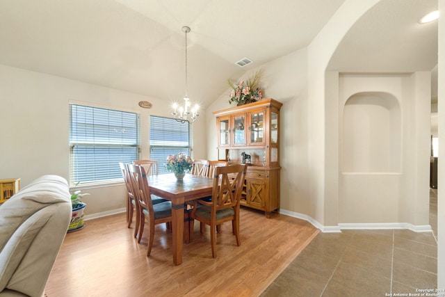 dining area featuring a notable chandelier, vaulted ceiling, and light hardwood / wood-style flooring