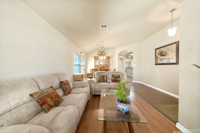 living room featuring an inviting chandelier, lofted ceiling, and dark wood-type flooring