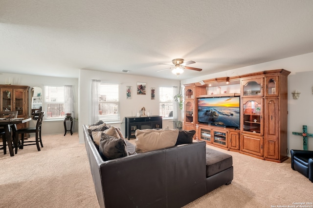 carpeted living room featuring ceiling fan and a textured ceiling