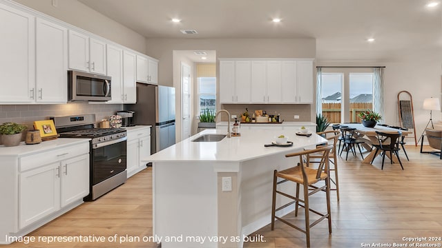 kitchen with white cabinets, appliances with stainless steel finishes, light wood-type flooring, and sink