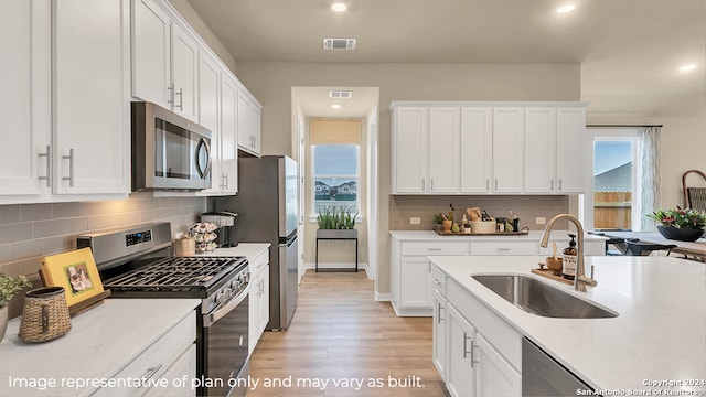 kitchen with white cabinets, appliances with stainless steel finishes, light wood-type flooring, and sink