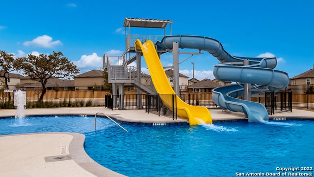 view of swimming pool featuring a playground, a water slide, and pool water feature