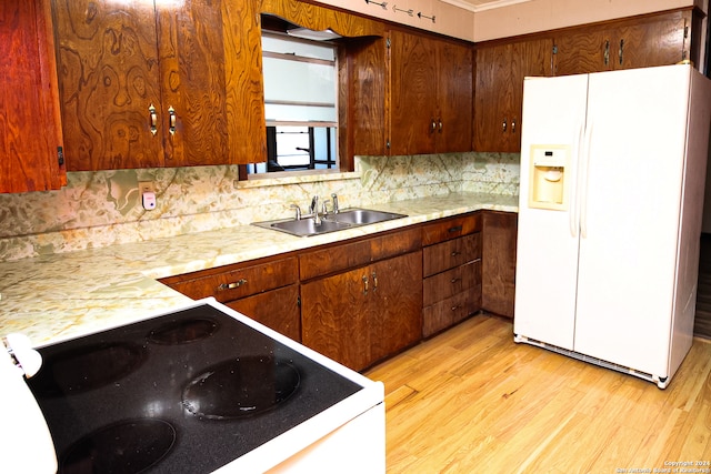 kitchen with light wood-type flooring, black stove, white refrigerator with ice dispenser, sink, and decorative backsplash