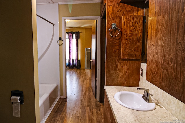 bathroom featuring wood-type flooring, a bathtub, ornamental molding, and vanity