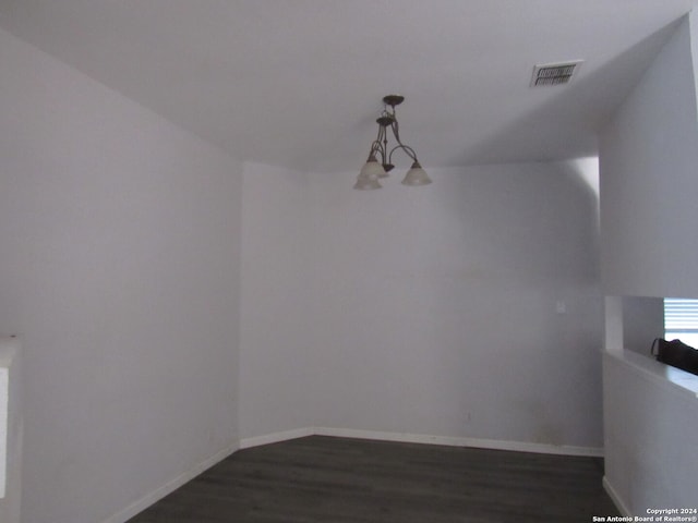 unfurnished room featuring dark wood-type flooring and a notable chandelier