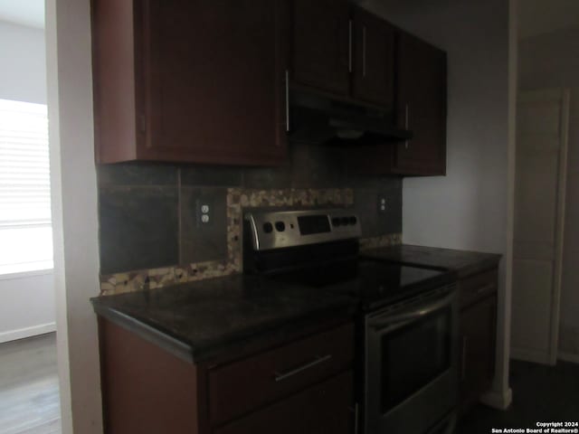 kitchen with tasteful backsplash, electric stove, and dark brown cabinetry