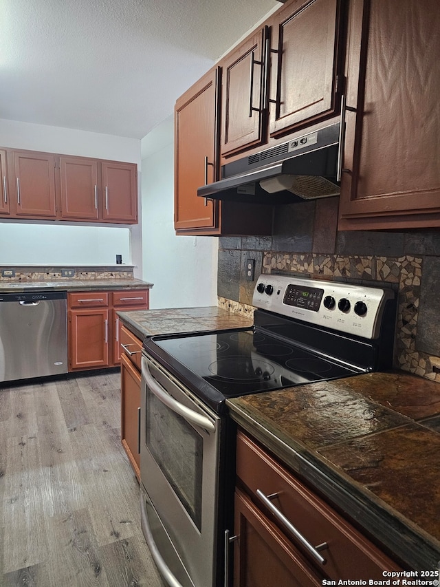 7731 Clear Ridge Dr, San Antonio, TX 78239 - kitchen featuring dark countertops, light wood-style flooring, appliances with stainless steel finishes, and under cabinet range hood