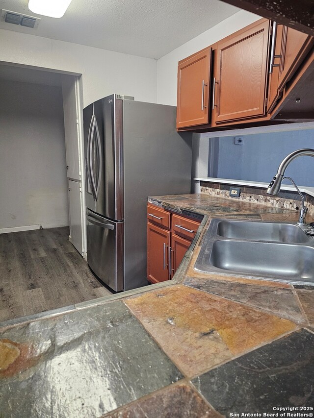 7731 Clear Ridge Dr, San Antonio, TX 78239 - kitchen featuring brown cabinets, freestanding refrigerator, visible vents, and a sink