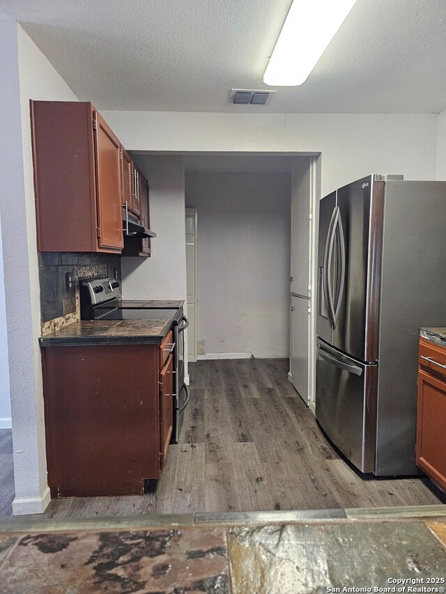 7731 Clear Ridge Dr, San Antonio, TX 78239 - kitchen featuring dark countertops, wood finished floors, extractor fan, appliances with stainless steel finishes, and visible vents