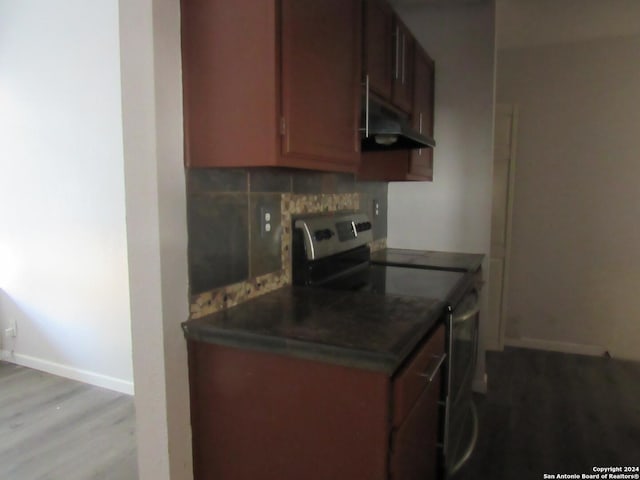 kitchen with electric range, decorative backsplash, and light wood-type flooring