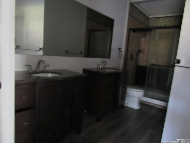 bathroom featuring a shower with door, vanity, hardwood / wood-style floors, and toilet