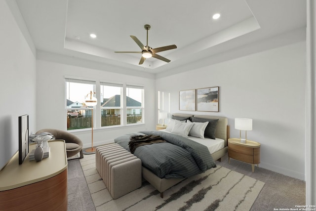 carpeted bedroom with ceiling fan and a tray ceiling