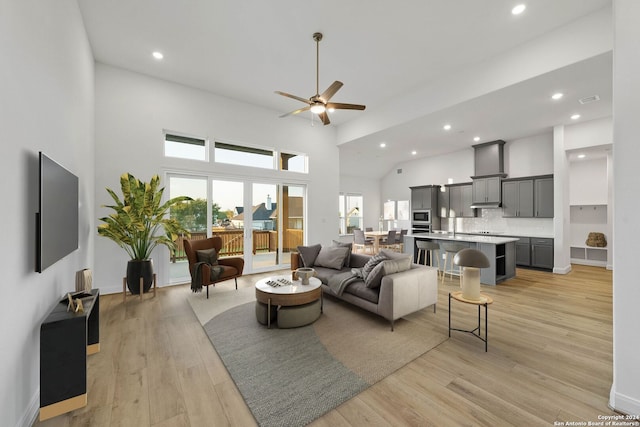 living room featuring ceiling fan, light hardwood / wood-style flooring, and a towering ceiling