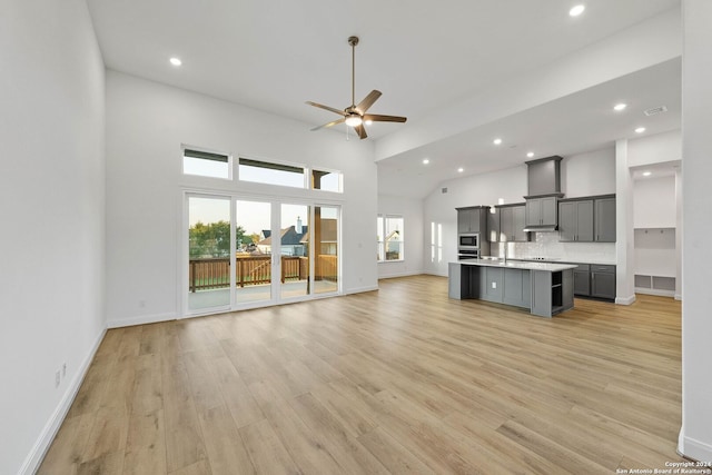 unfurnished living room with ceiling fan, light hardwood / wood-style flooring, and a towering ceiling