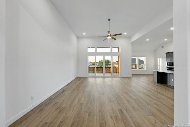 unfurnished living room featuring ceiling fan, light hardwood / wood-style flooring, and high vaulted ceiling