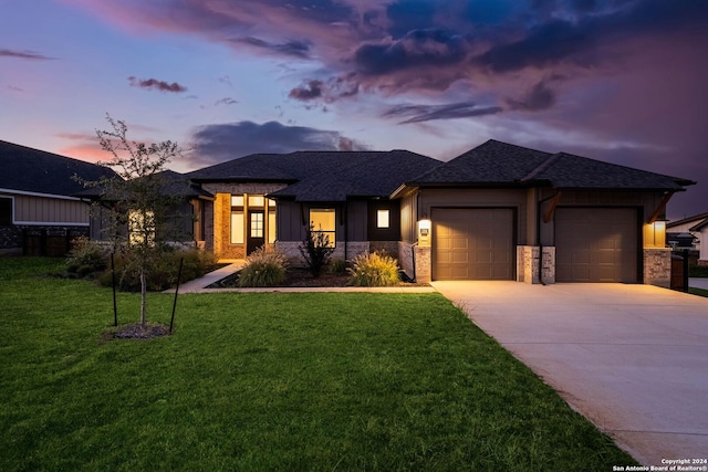 prairie-style home featuring a garage and a lawn